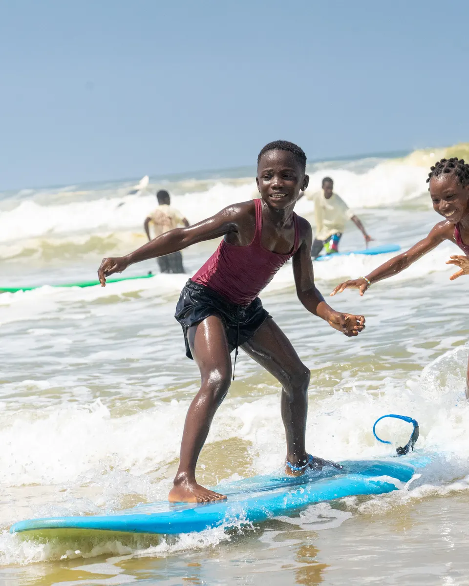 Deux filles qui rient en glissant sur une planche en mousse, dans les vagues du bord.