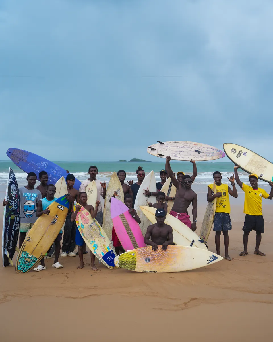 Des enfants sur la plage brandissent des planches de toutes les couleurs.