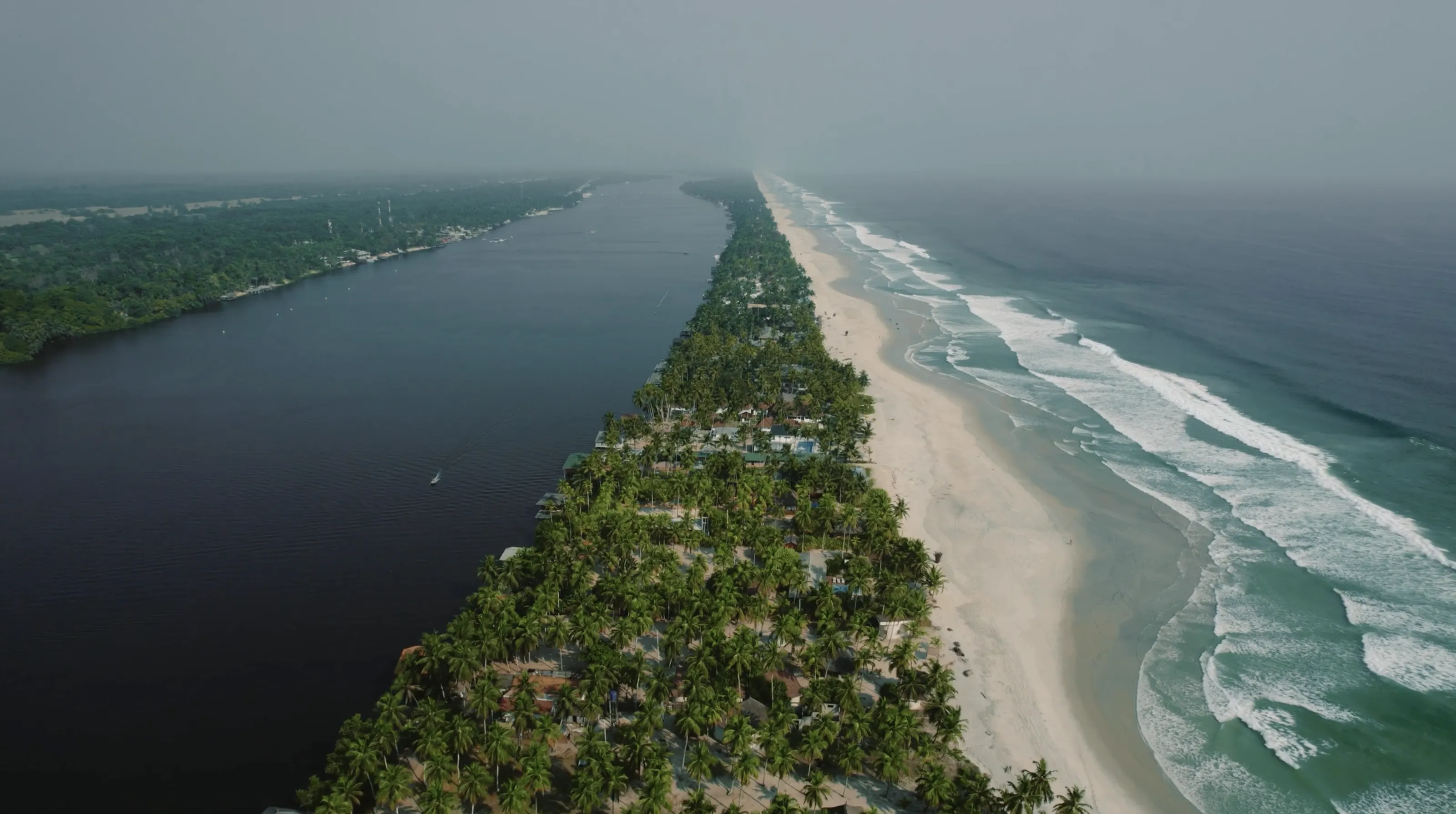 Assinie from the air: the lagoon, the strip of palm trees and the beach, and the Atlantic rolling in.