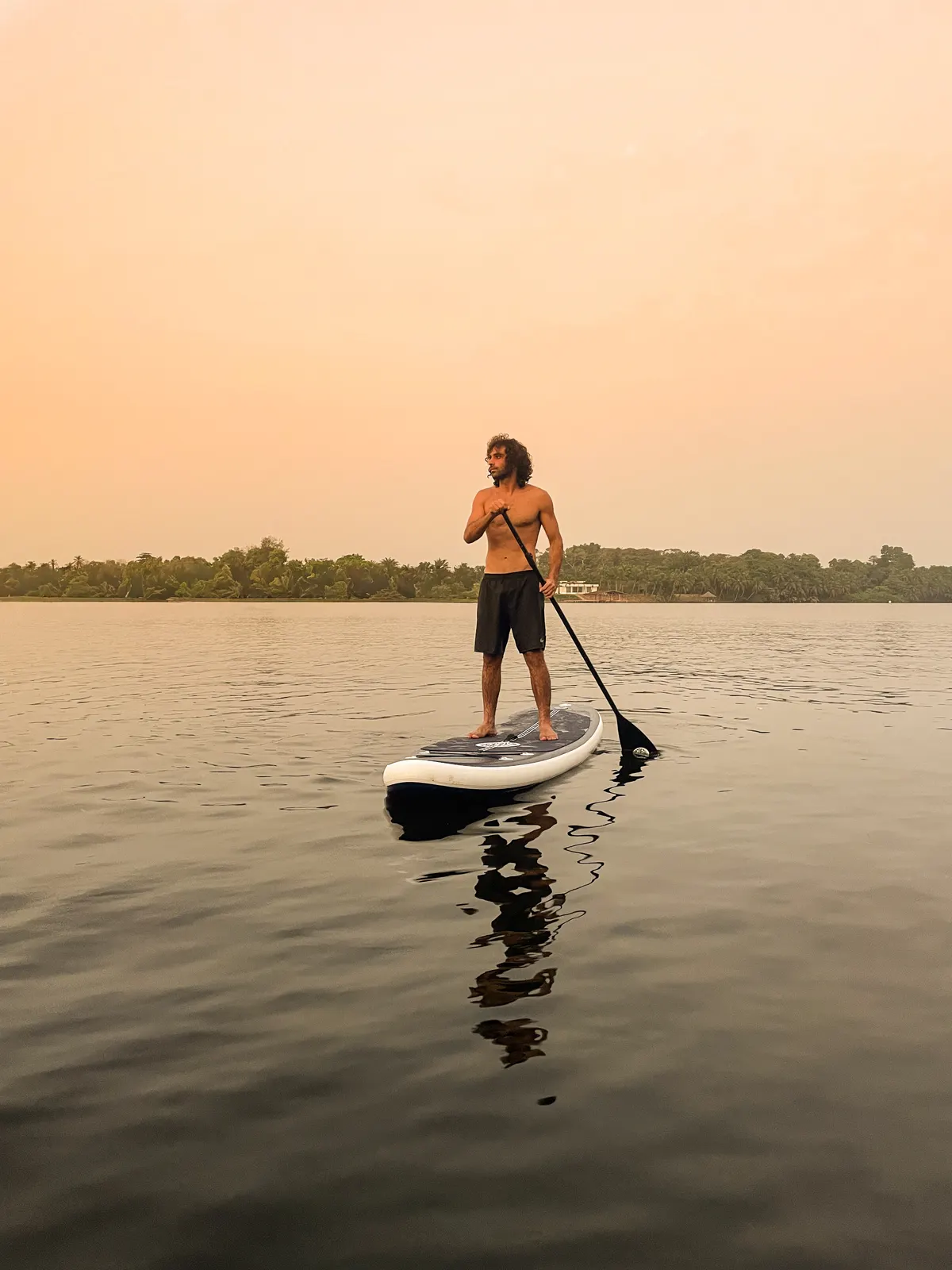 A paddleboarder on the calm lagoon at sunset.