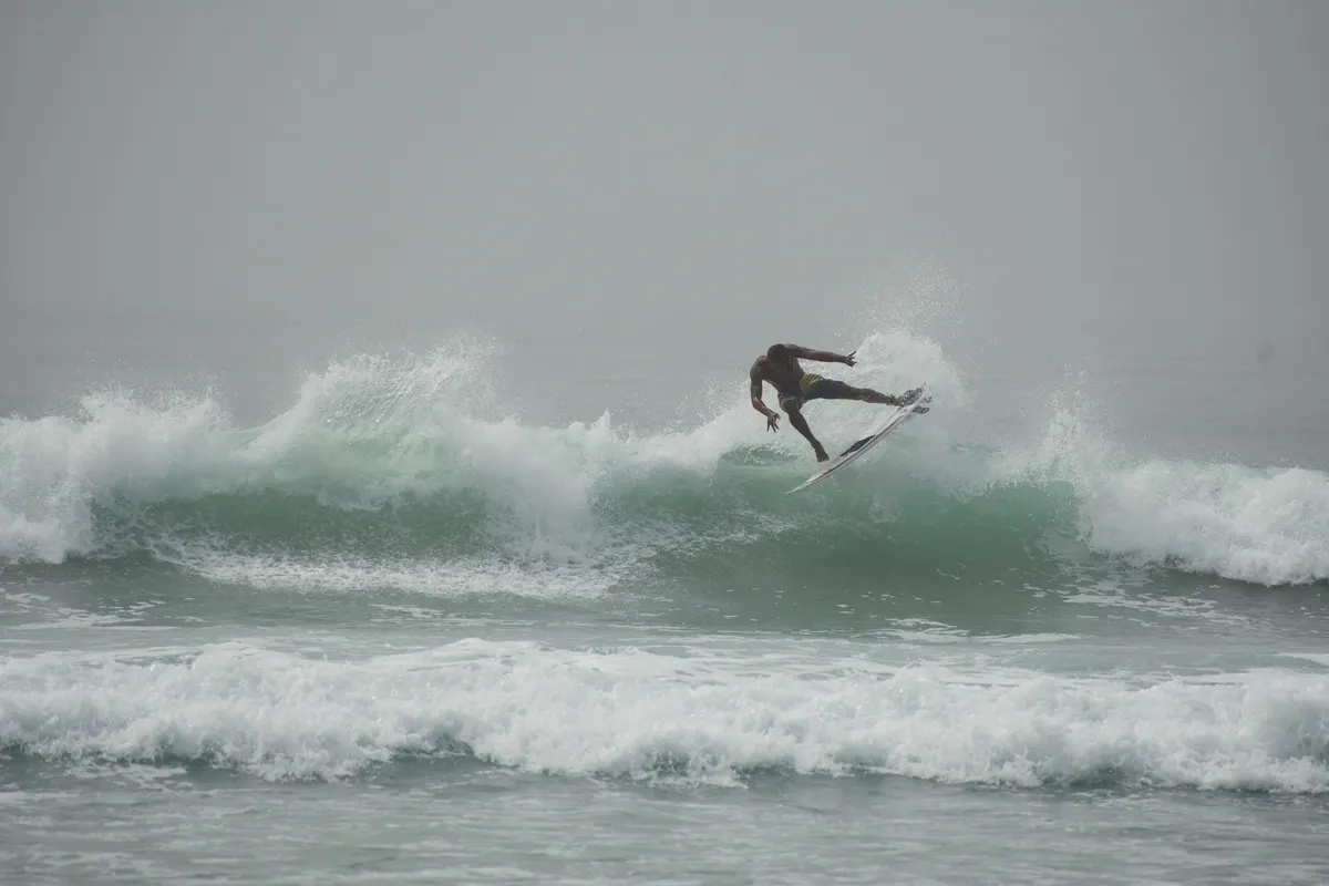 A surfer launching into the air above a breaking wave.