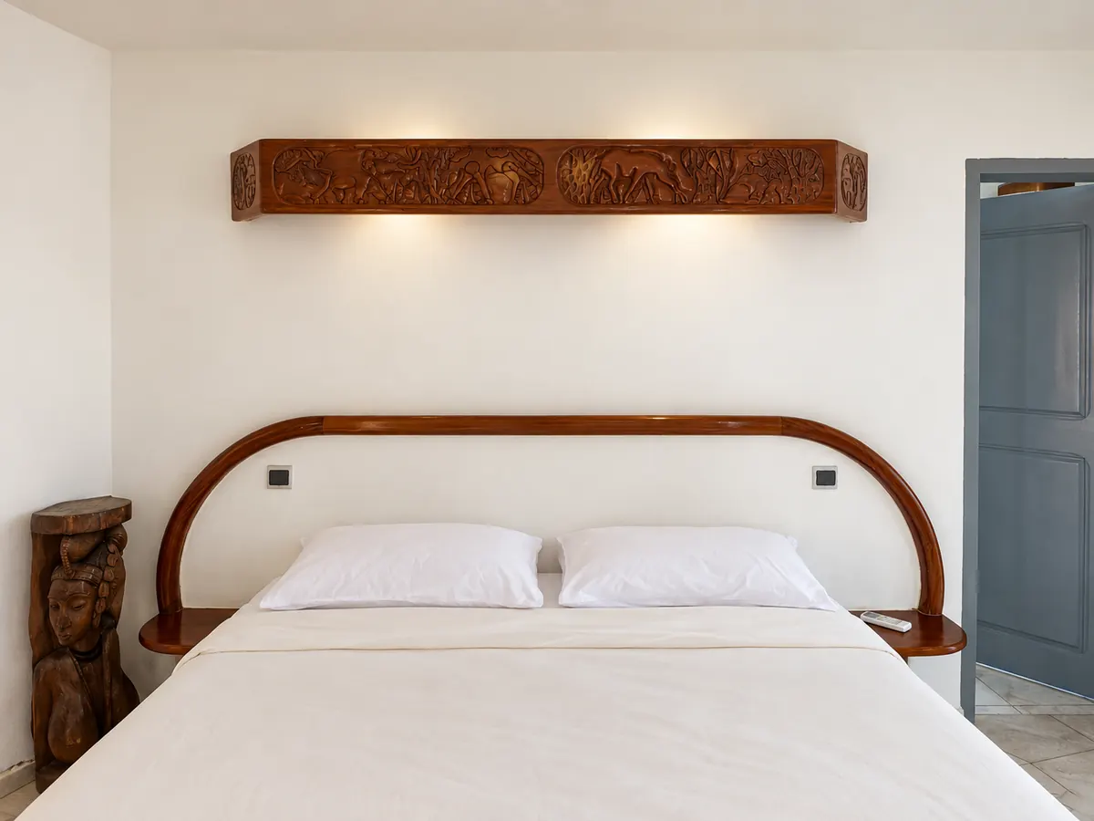 The premium double: a double bed with a curved wooden headboard under a carved wooden shelf.