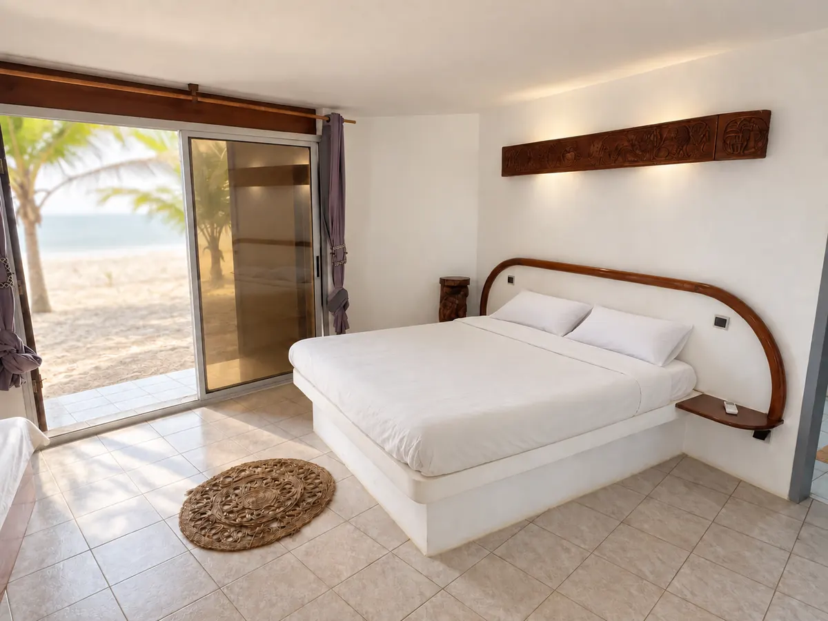 The bed facing open glass doors, with palm trees and the beach outside.