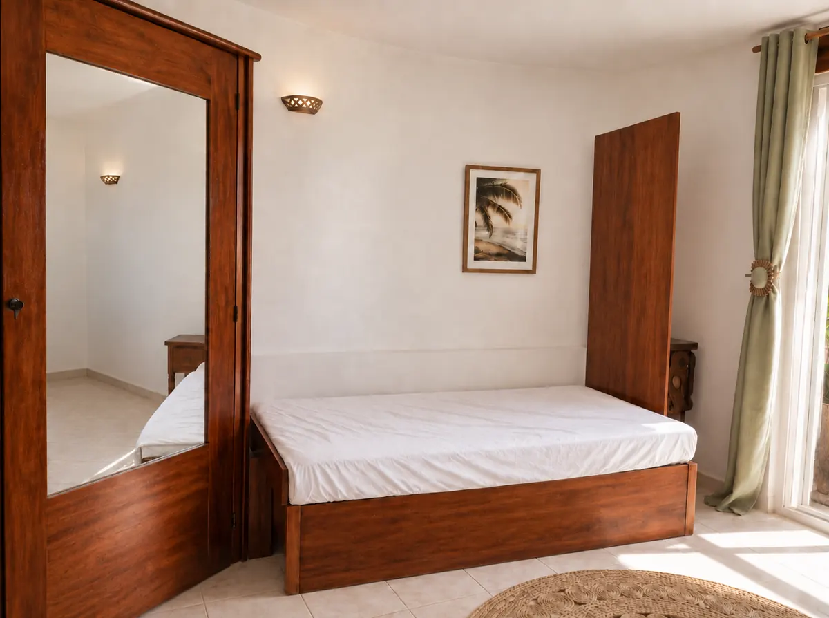 A wooden wardrobe with a full-length mirror beside the bed.