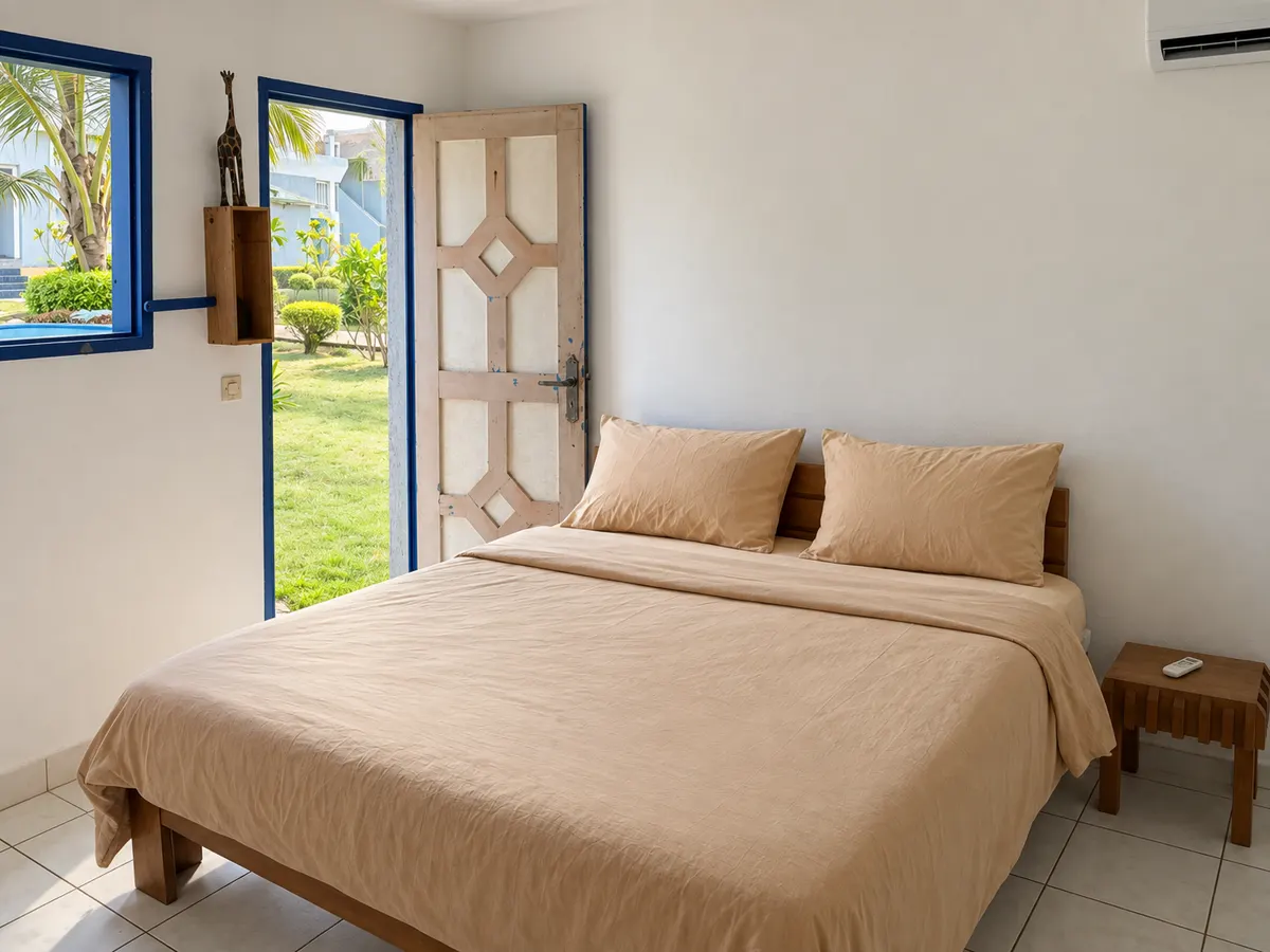 Another superior bedroom: a double bed, the door open onto the garden and palm trees.
