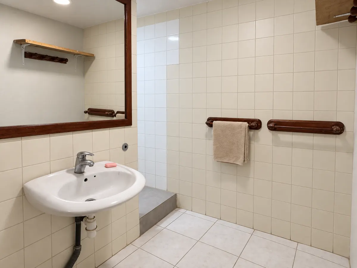 The shared bathroom: a washbasin under a wooden-framed mirror and a tiled shower.