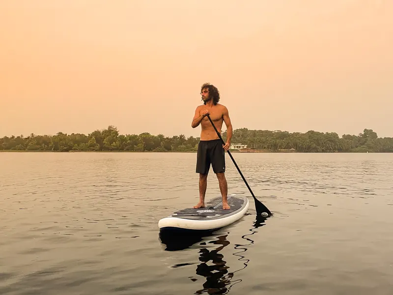 A man on a paddleboard on the calm lagoon at dusk.
